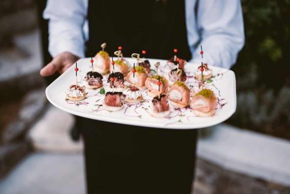 Canapés para eventos; mesero sosteniendo un plato con comida.