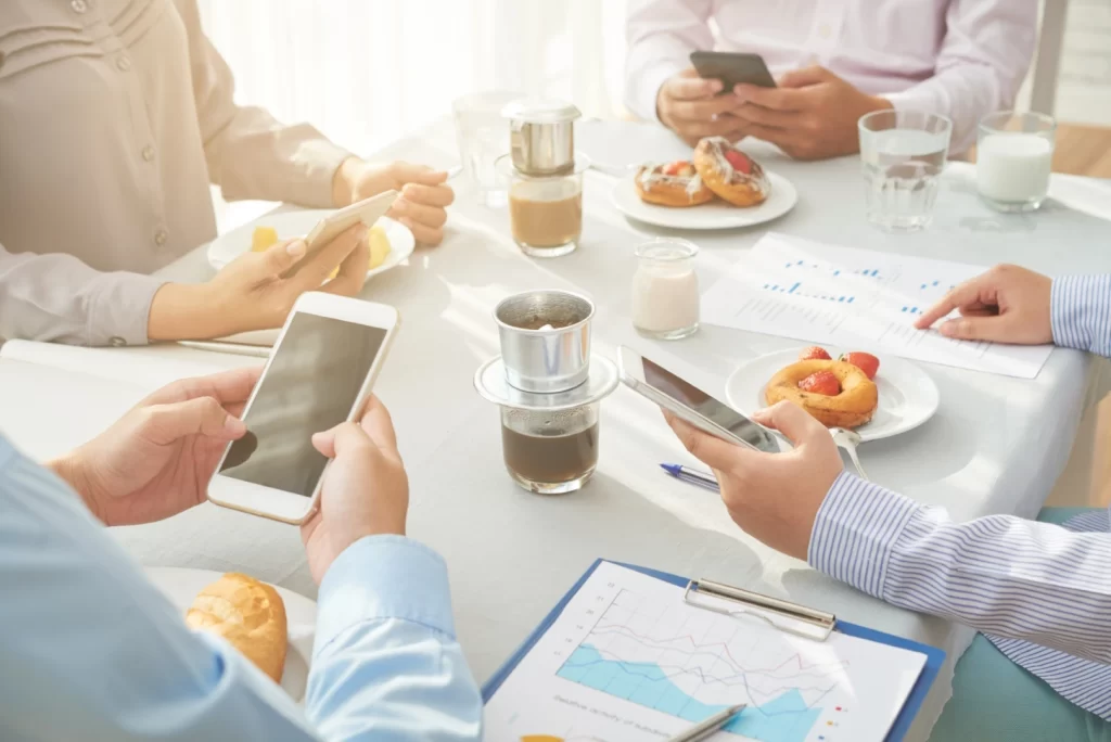 Coffe Break Ejecutivo 2; Celulares y alimentos y bebidas sobre una mesa blanca.