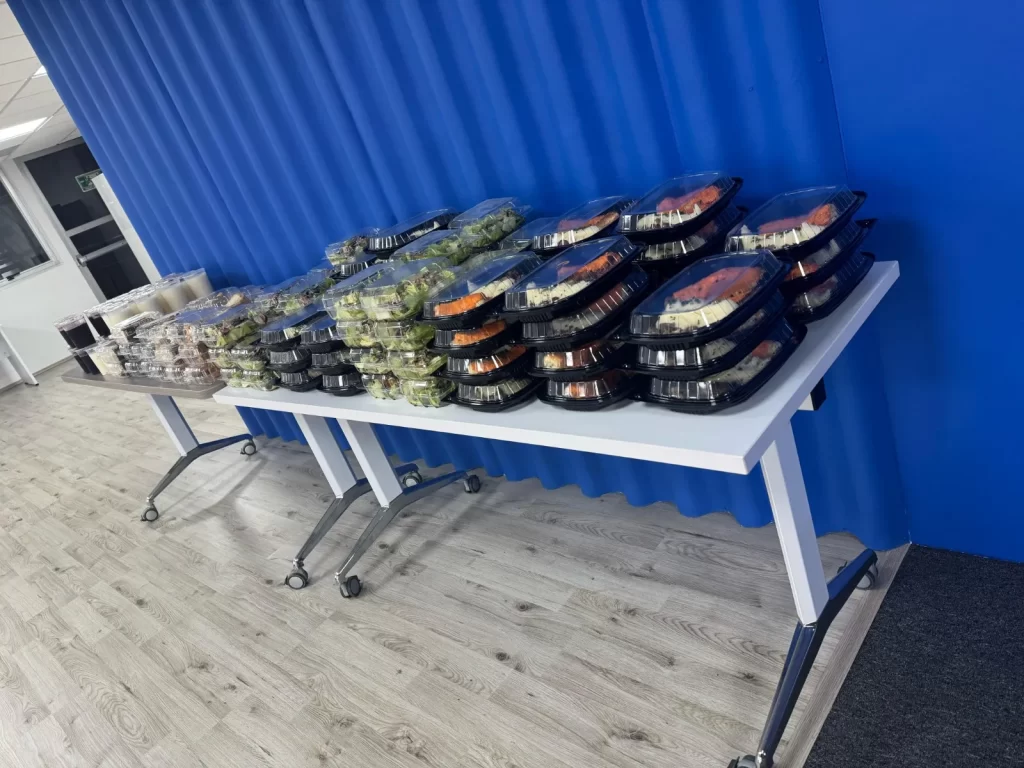 Muchas charolas de comida que están cerradas, tiene diferentes tipos de comida, todo listo para catering box lunch, todo puesto sobre una mesa