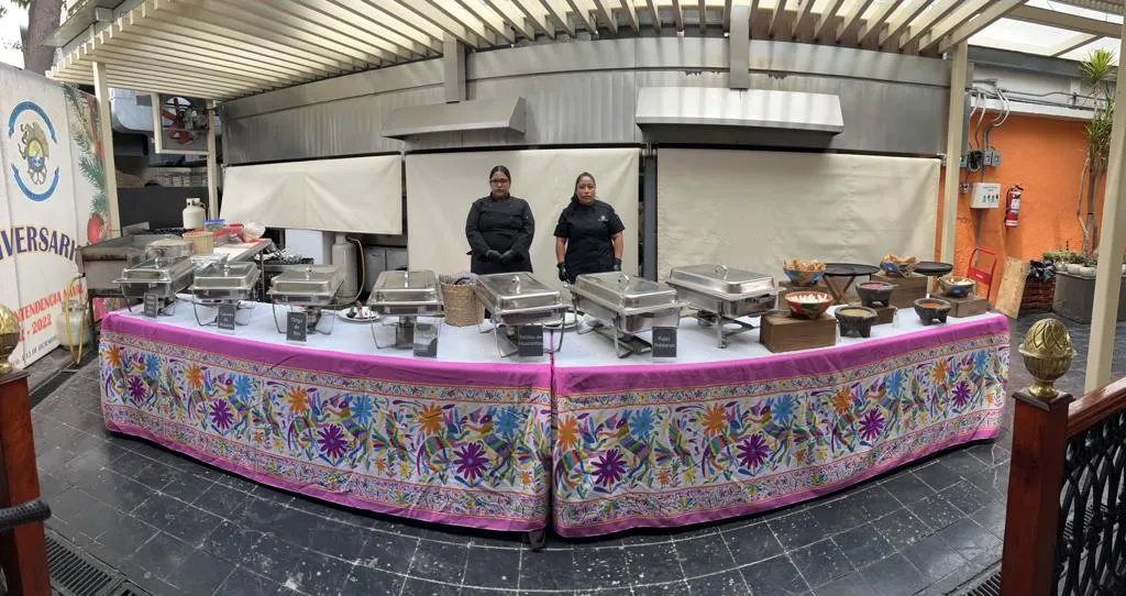 Unas personas detrás de una mesa con ingredientes para los servicios de taquizas para eventos