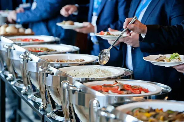 Una comida para eventos, hay varios trabajadores de una empresa que se están sirviendo