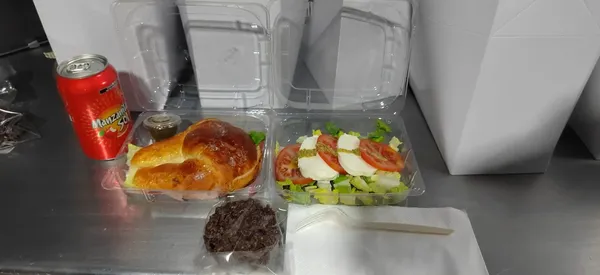 Sobre una mesa hay una charolas de plástico con comida, son un box lunch