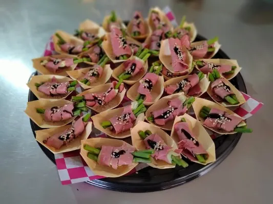 Hay una bandeja que tiene canapés y bocadillos, sobre una mesa