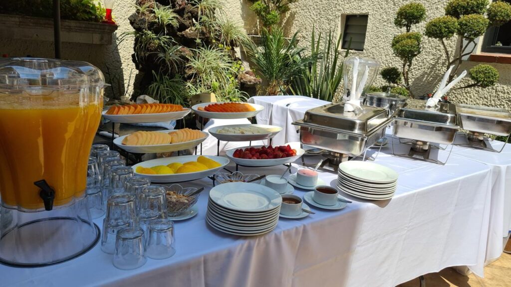 Montaje de coffee break al aire libre presenta una mesa cubierta con un mantel ofreciendo café caliente