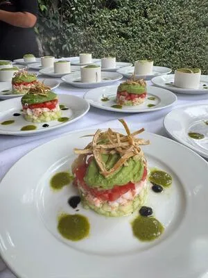 Primer plano de una torre gourmet de aguacate, tomate, camarón y pepino, adornada con tiras de tortilla frita. Alta cocina en la mejor comida para eventos.