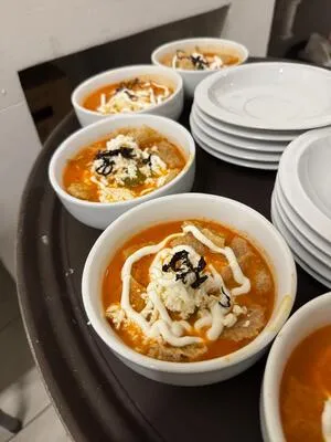 Charola con tazones individuales de sopa caliente, adornada con queso y crema, lista para servir. Esta es una opción cálida de comida para eventos.