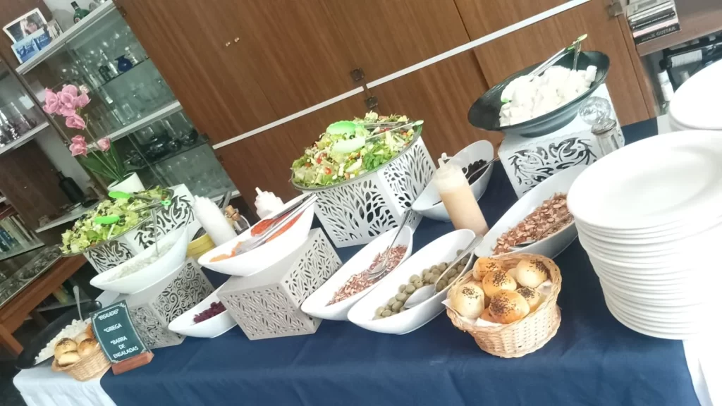 Variedad de ensaladas, aderezos y pan artesanal presentados en una barra para un servicio de catering saludable.