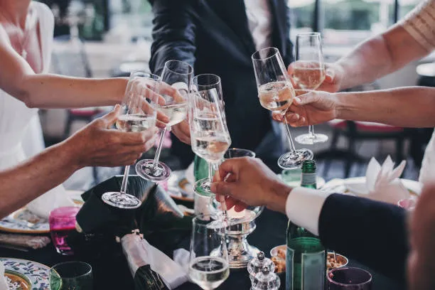 Invitados realizando un brindis con champaña durante el servicio de banquetes para fiestas y celebraciones especiales.
