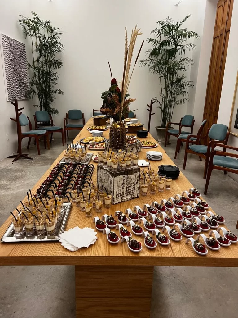 Mesa de postres con fresas con chocolate y mini parfaits en un elegante servicio de catering para eventos.