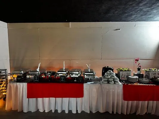 Buffet con estaciones de comida caliente y mantelería fina, ideal en el servicio de banquetes para graduación escolar.