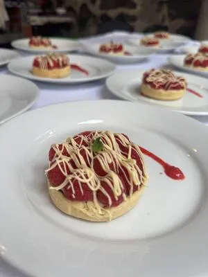Delicada tartaleta de frambuesa con chocolate blanco, el postre ideal en un banquete para cumpleaños gourmet y elegante.