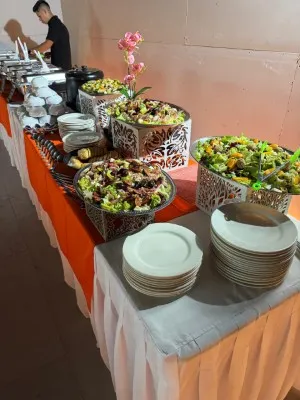Buffet de ensaladas gourmet con flores rosas, ideal para banquetes para bodas en primavera al aire libre o de día.