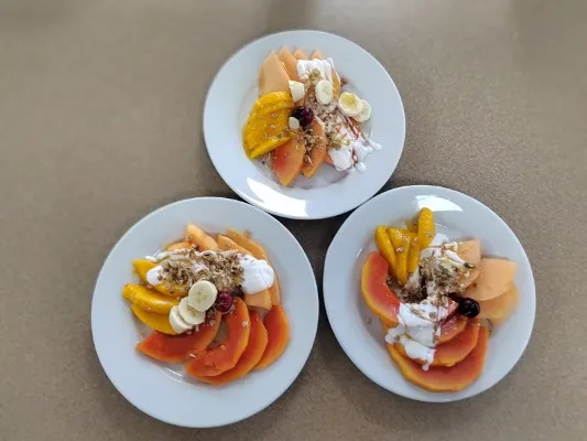 Plato de papaya, mango y plátano con granola y yogurt, la opción saludable que destaca en varios tipos de brunch.