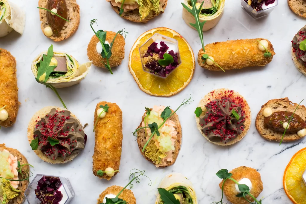 Vista superior con diferentes opciones de canapes y bocadillos sofisticados y coloridos presentados sobre una mesa.