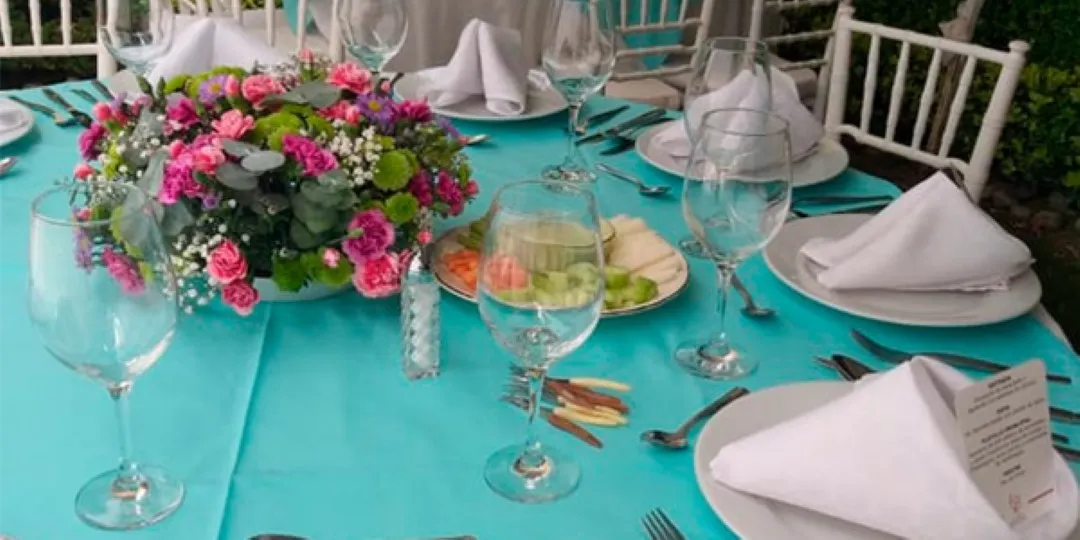 Decoración de mesas con mantelería turquesa y flores frescas para banquetes para eventos sociales y bodas de día.