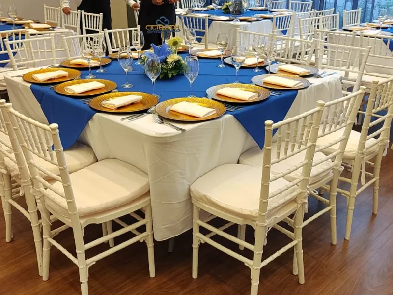 Banquetes para eventos empresariales, hay sillas alrededor de una mesa, la mesa tiene mantel blanco y azul