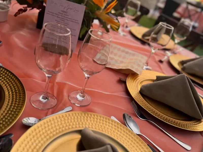 El mobiliario de los servicios de banquetes está acomodado, hay un mantel rojo con platos y servilletas