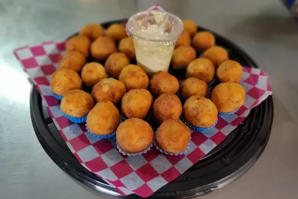 Bandeja con canapes y bocadillos de croquetas fritas esféricas acompañadas de un aderezo central para eventos de gala.
