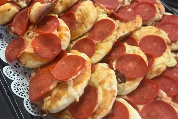 Mini pizzas de pepperoni listas para servir en servicios de canapes y bocadillos para fiestas y reuniones sociales.